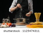 The chef prepares spaghetti and pasta, salt water, against a dark background, the concept of cooking