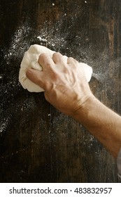 Chef Preparing Pizza Dough Kneading It With His Hand On A Floured Kitchen Counter, Overhead Close Up View