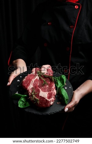 A chef preparing ribeye beef steak. Aged and matured steak. Meat. On a black background.