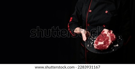 A chef preparing ribeye beef steak. Aged and matured steak. Meat. On a black background.