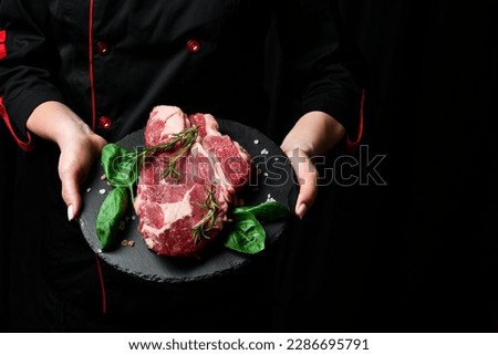 A chef preparing ribeye beef steak. Aged and matured steak. Meat. On a black background.