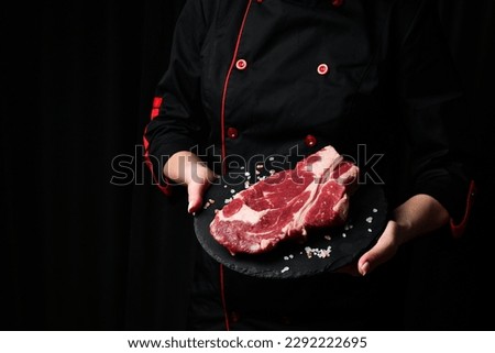 A chef preparing ribeye beef steak. Aged and matured steak. Meat. On a black background.