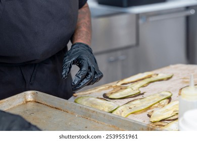 Chef preparing sliced zucchini on a baking tray in a modern kitchen during a culinary session - Powered by Shutterstock