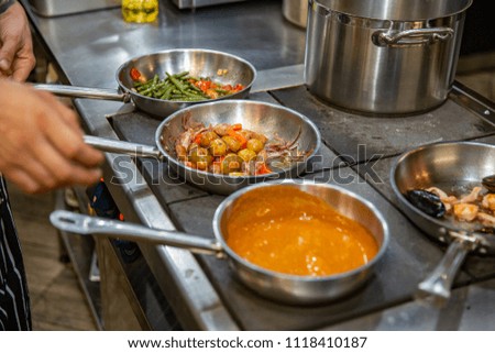 Chef preparing vegetables on frying pan in the professional kitchen.
