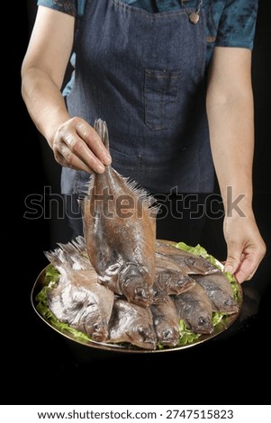 Chef presenting exceptionally fresh deep sea fish from Dalian on platter with greens, showcasing premium seafood batch for culinary preparation