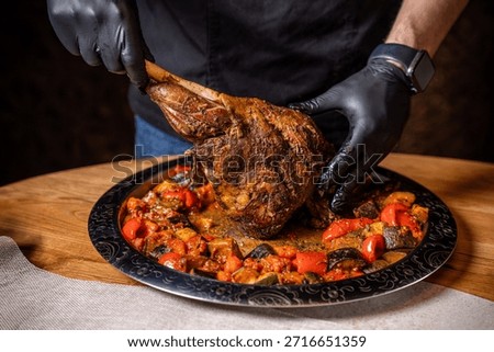 Chef presenting a roasted lamb leg over baked vegetables on a large platter highlighting halal friendly festive cuisine and rich traditional restaurant flavors