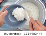 Chef put cooked rice with plastic ladle to cup in electric rice cooker