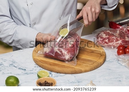 Chef puts lime in a vacuum bag with meat on a blurred background.
