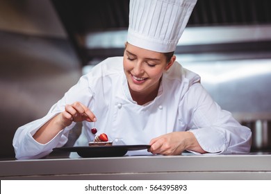 Chef putting a cherry on a dessert in a commercial kitchen - Powered by Shutterstock