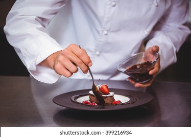 Chef putting chocolate sauce on a dessert in a commercial kitchen - Powered by Shutterstock