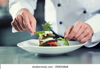 Chef in Restaurant garnishing vegetable dish, crop on hands, filtered image - Shutterstock ID 390054868