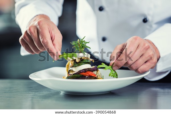 Chef in Restaurant garnishing vegetable dish, crop\
on hands, filtered image