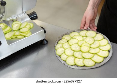 The chef in the restaurant kitchen prepares zucchini slices with a slicer - Shutterstock ID 2256897327