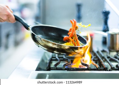Chef in restaurant kitchen at stove with pan, doing flambe on food - Shutterstock ID 113264989