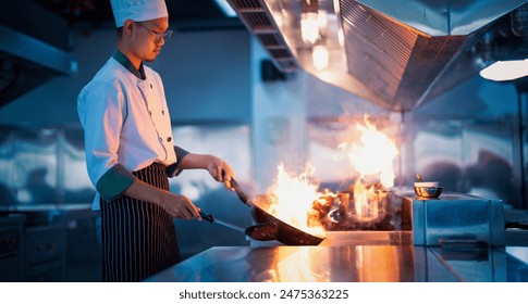 Chef in restaurant kitchen at stove and pan cooking flambe on food - Powered by Shutterstock