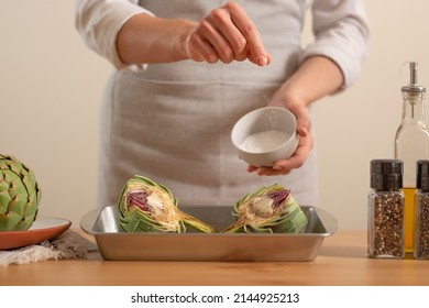 Chef Salt And Prepare To Bake The Artichoke On A Light Background, The Concept Of Cooking Tasty And Healthy Food, Menus, Recipe Book, Detox, Organic Produce Or Local Market Concept