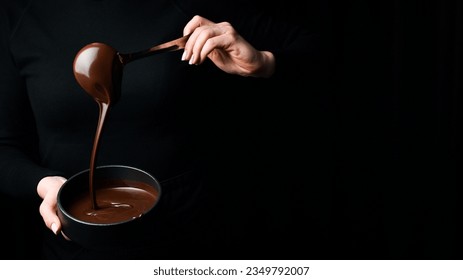 The chef scoops hot chocolate into a bowl. On a black background. Preparation of chocolate. - Powered by Shutterstock