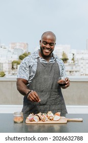 Chef seasoning barbeque skewers at a rooftop party