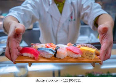 Chef served Japanese Sushi on wooded plate by hand to customer, This immage can use for Restaurant, food, Japan, Japanese food, shushi, seafood, fish and salmon concept