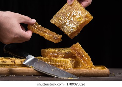 The chef serves bee honey in combs with his hands. Close up on a wooden table. Organic farm food concept.
