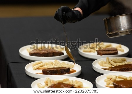 chef is serving pasticada with gnocchi, beef stew in a sauce. Croatian cuisine