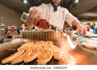 Chef setting oil on fire for flambing in japanese teppanyaki restaurant, closeup