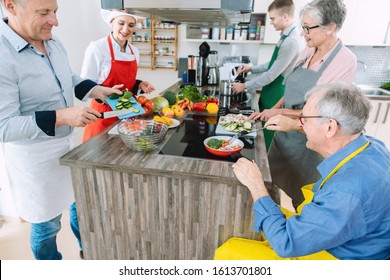 Chef showing mixed group of trainees the secrets of healthy cooking in her kitchen - Powered by Shutterstock