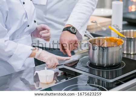 Chef shows how to use electric stove at cuisine of restaurant. Professional cooking, training, education, learning, instruction, catering, cookery, gastronomy and food concept