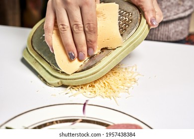 A Chef Shredding Cheese To Sprinkle On Pizza