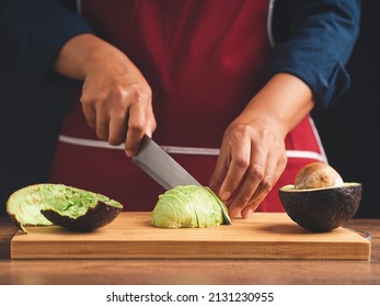 Chef slicing avocado on a wooden cutting board with the knife. Healthy fruit and food eating concept. Close-up photo - Powered by Shutterstock