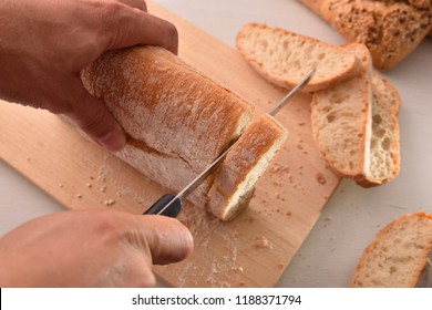 Chef Slicing Bread In Slices On A Cutting Board In A Kitchen Bench. Top View. Horizontal Composition