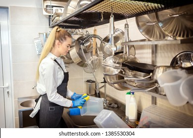 Chef Of Small Restaurant Washing Dishes In Sink At End Of Working Day – Kitchen Worker Using Sponge To Clean Dishes – Young Woman At Work In Eatery Kitchen