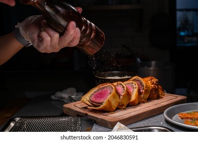 Chef spreading black pepper in beef Wellington platter at high cuisine restaurant's kitchen - Shutterstock ID 2046830591
