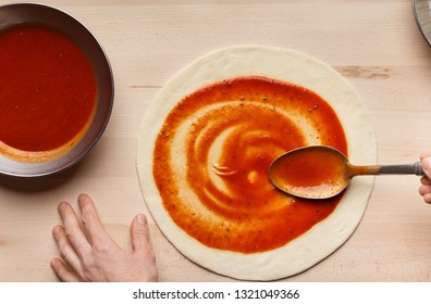 Chef Spreading Tomato Paste On Pizza Base, Top View