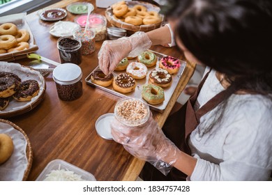 Chef sprinkled donuts with nuts and decorated donuts on the table in the kitchen - Powered by Shutterstock