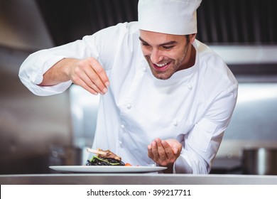 Chef sprinkling spices on dish in commercial kitchen - Shutterstock ID 399217711