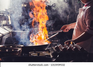 Chef Stir Fry In Wok. Dramatic Cooking With Fire Hard