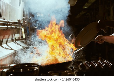 Chef Stir Fry In Wok. Dramatic Cooking With Fire Hard