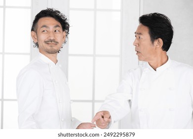 Chef supervisor and subordinate arguing in the kitchen. Chef and sous-chef. Chef snaps in anger at lickspittle subordinate. - Powered by Shutterstock