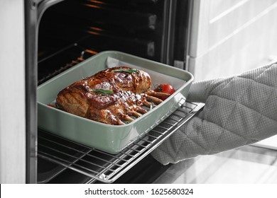 Chef taking delicious roasted ribs out of oven, closeup - Powered by Shutterstock