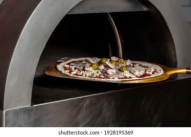 Chef Taking Raw Pizza On Metal Shovel. Restaurant Chef Takes Pizza From Oven In Traditional Restaurant. Preparing Traditional Italian Pizza.