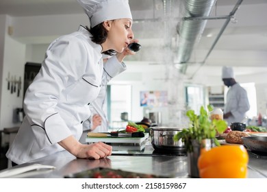 Chef tasting gourmet dish cooked in professional kitchen and served at dinner service in fine dining restaurant. Gastronomy expert checking food taste before send it to customers. - Powered by Shutterstock