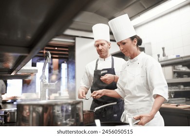 Chef, teamwork and cooking in kitchen at stove or preparation of food for fine dining, cuisine or hospitality. Man, woman and service as restaurant career or recipe for dinner rush, meal or nutrition - Powered by Shutterstock