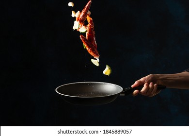 The Chef Toss Up King Crab Legs With Pieces Of Lime In A Frying Pan On Dark Blue Background. Seafood Concept. Frozen Motion. Backstage Of Preparing Traditional Thai Recipe.