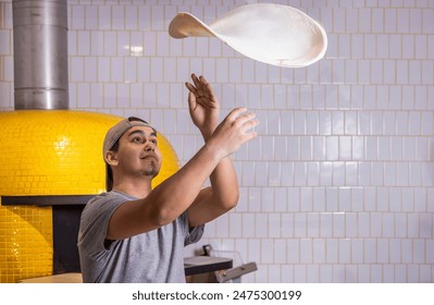 Chef tosses the pizza dough into the air. Hands of a male chef with thin round pizza dough in the kitchen.Skilled chef preparing dough for pizza rolling with hands and throwing up. - Powered by Shutterstock