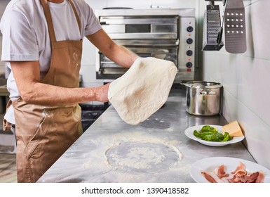 Chef tossing pizza dough at pizzeria kitchen - Powered by Shutterstock