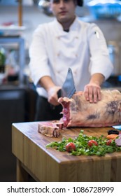 chef using ax while cutting big piece of beef  on wooden board in restaurant kitchen - Shutterstock ID 1086728999
