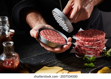 Chef using a burger press to prepare fresh homemade ground beef patties in a takeaway restaurant in a close up on his hands and the utensil - Powered by Shutterstock