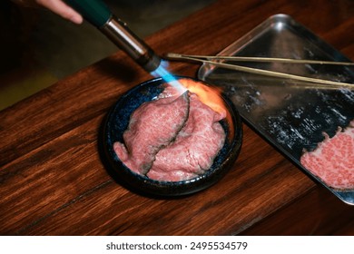 Chef using kitchen torch burn on sliced of beef in rice bowl. Fresh beef raw sliced with marbled texture. - Powered by Shutterstock