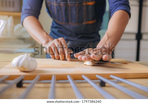 Chef using knife to smashing the fresh\
garlic, prepare for home cooking in modern\
kitchen.